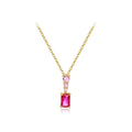 A yellow gold necklace featuring a rectangular emerald-cut pink gemstone pendant, accented by a smaller round pink gemstone and tiny clear stones on the chain, set against a solid white background.
