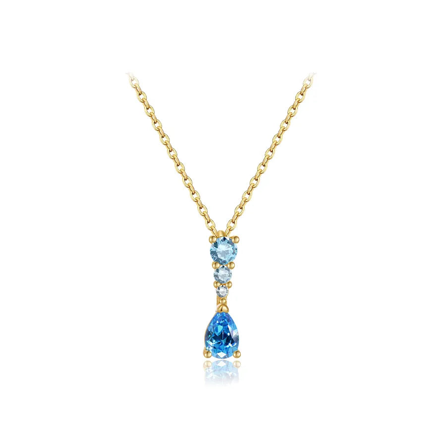 A gold necklace featuring a drop pendant with a small round light blue gemstone, a tiny clear accent stone, and a larger teardrop-shaped blue gemstone below, set against a plain white background.