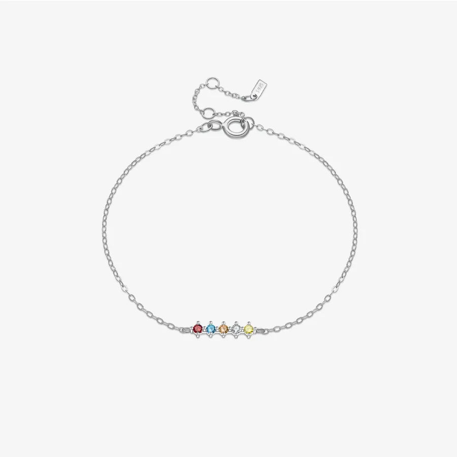 A delicate silver chain bracelet with a small central bar set with five tiny colorful gemstones, displayed on a light gray background.