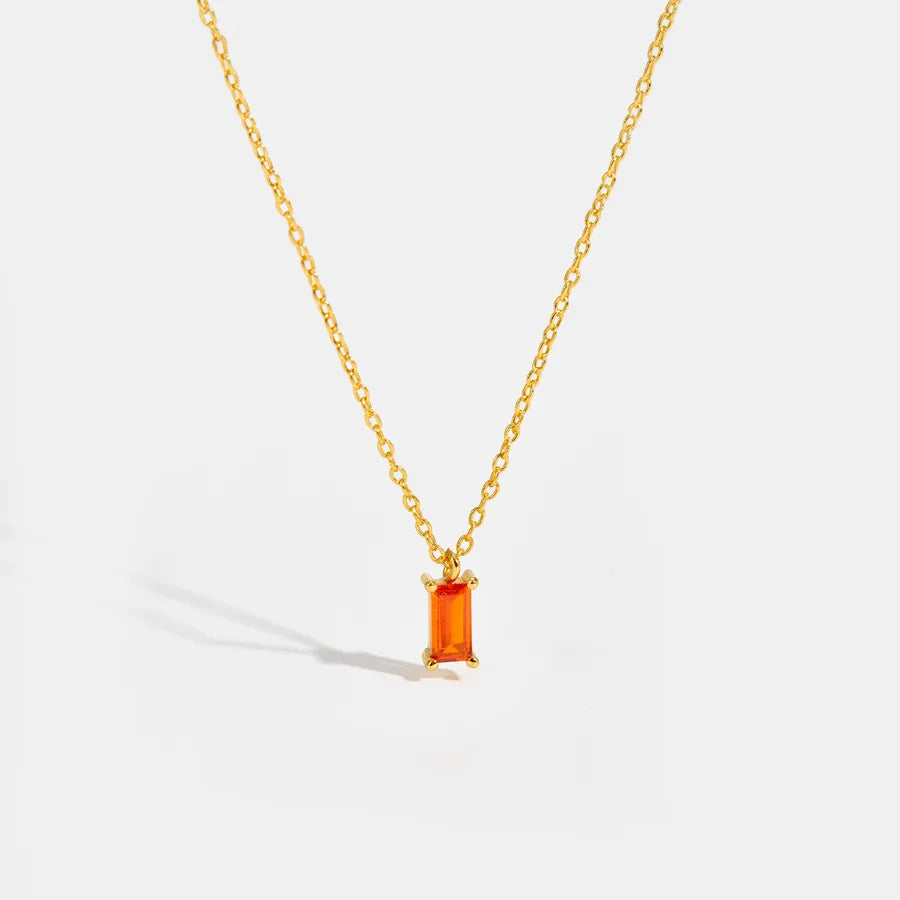 A delicate gold chain necklace featuring a small rectangular orange gemstone pendant, displayed against a clean white background with a soft shadow.
