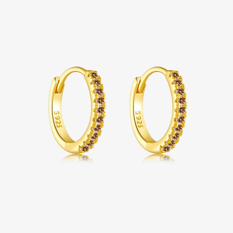 A pair of gold huggie hoop earrings with a row of small round brown gemstones, featuring a 5.925 sterling silver mark on the inner band, set against a light gray background.