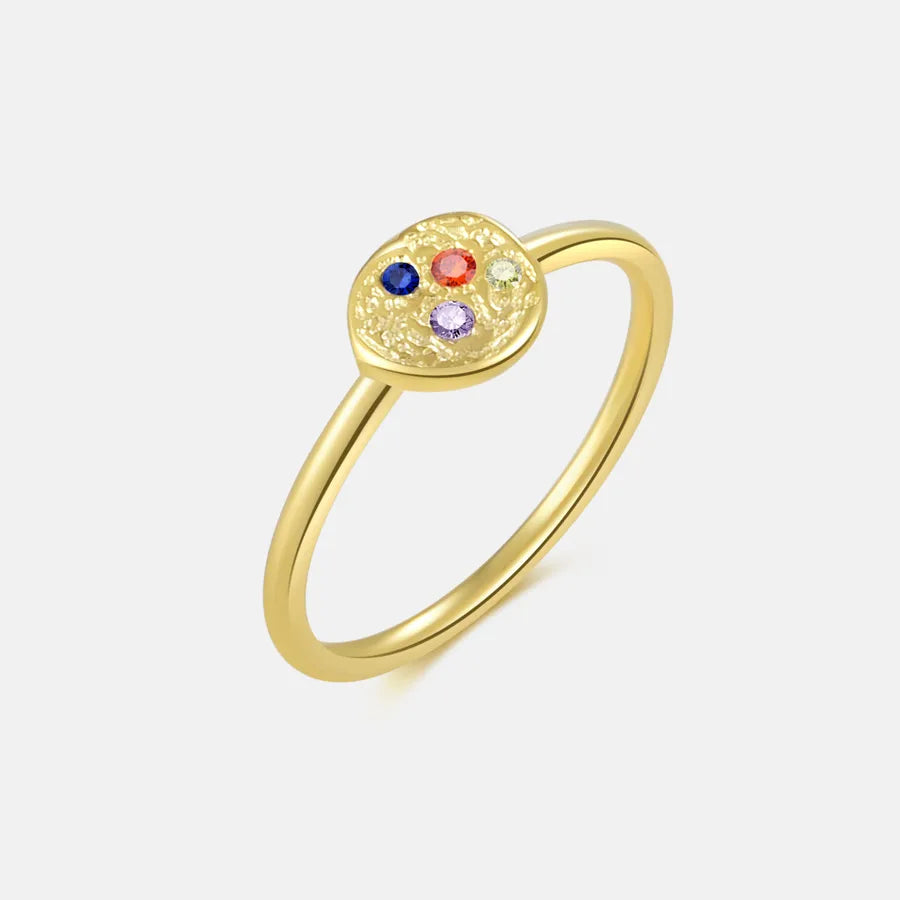 Gold ring with colorful gemstones on a light gray background