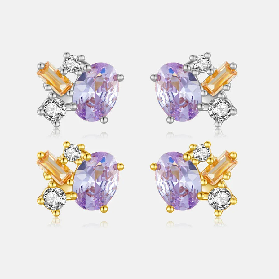 Four pairs of stud earrings arranged in a 2x2 grid on a light gray background. Each pair features an oval light purple gemstone surrounded by a cluster of clear round stones and rectangular orange-yellow baguette stones in silver and gold settings.