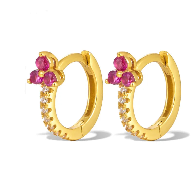 Gold hoop earrings with pink gemstones on a white background