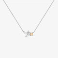 A delicate silver chain necklace featuring a small pendant with two silver leaves and a central clear crystal, accented by a small peach-colored heart-shaped gemstone, shown on a light gray background.