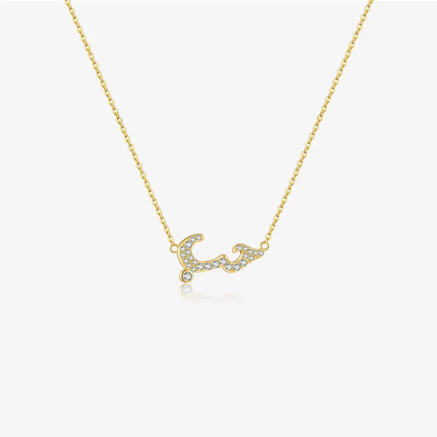 A delicate gold chain necklace featuring a Arabic letters pendant paved with small clear stones, displayed against a clean white background.