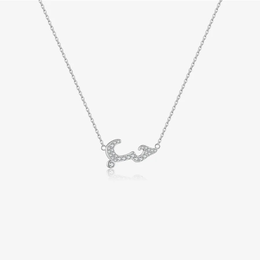 A delicate silver chain necklace featuring a arabic letters pendant embellished with small clear stones, displayed against a light gray background.