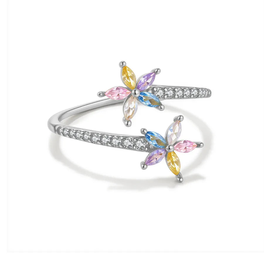 A silver-tone open bangle ring decorated with two butterfly motifs set with marquise-cut crystals in pastel pink, yellow, blue, and purple, accented by small clear stones along the band, shown on a white background.