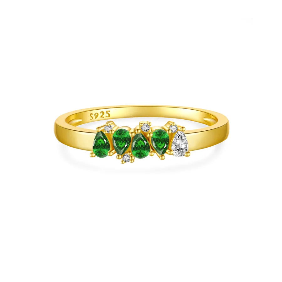 Gold ring with green gemstones and diamonds on a white background