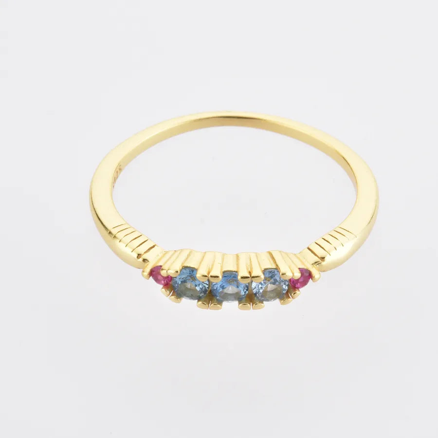 Gold ring with colorful gemstones on a light gray background