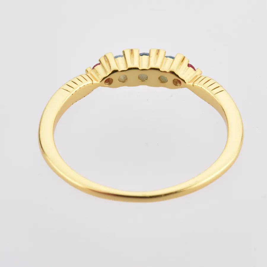 Gold ring with embedded gemstones on a light gray background