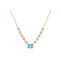 A gold necklace featuring a central rectangular light blue gemstone pendant, flanked by smaller round clear stones in bezel settings along the chain, shown on a plain white background.