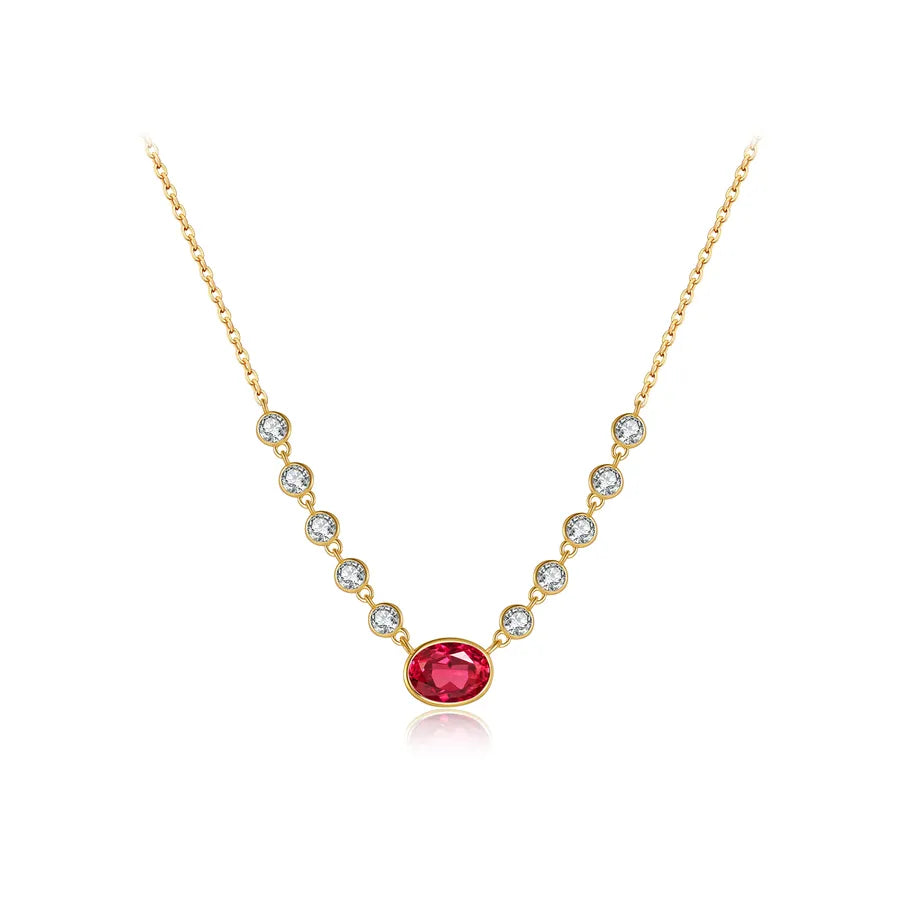 A delicate gold chain necklace featuring a central oval-cut pinkish-red gemstone, flanked by a series of small clear round-cut stones in gold bezel settings, shown on a pure white background.