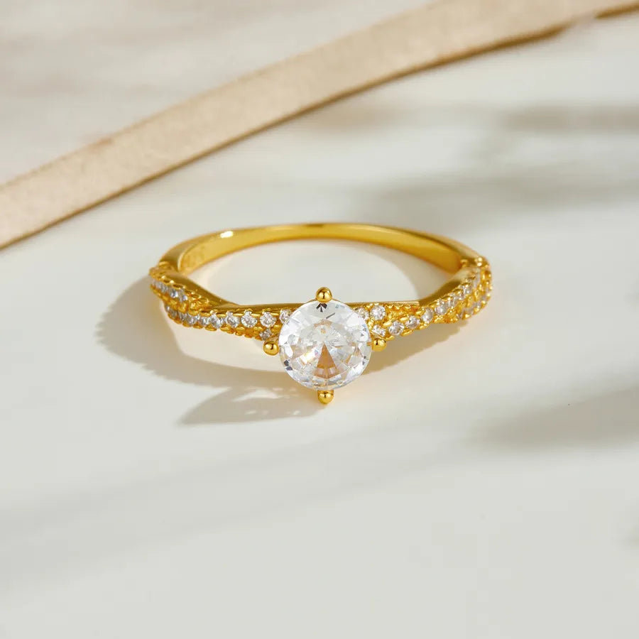 Gold ring with a large central gemstone and smaller stones on a beige background
