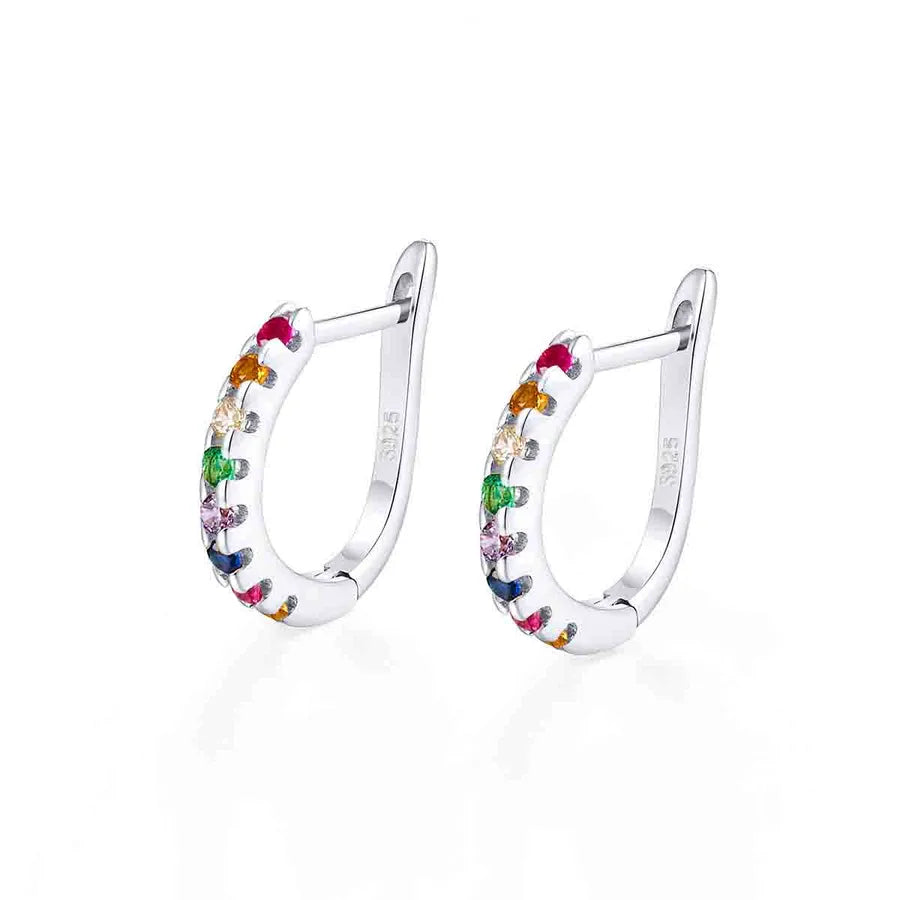 A pair of silver huggie hoop earrings decorated with small, colorful gemstones in pink, orange, yellow, green, blue, and purple, set against a clean white background.