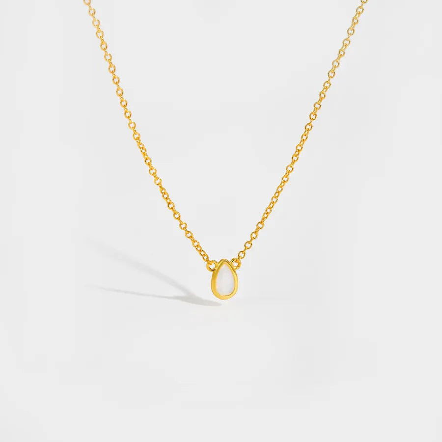 Gold necklace with a small pendant on a light gray background
