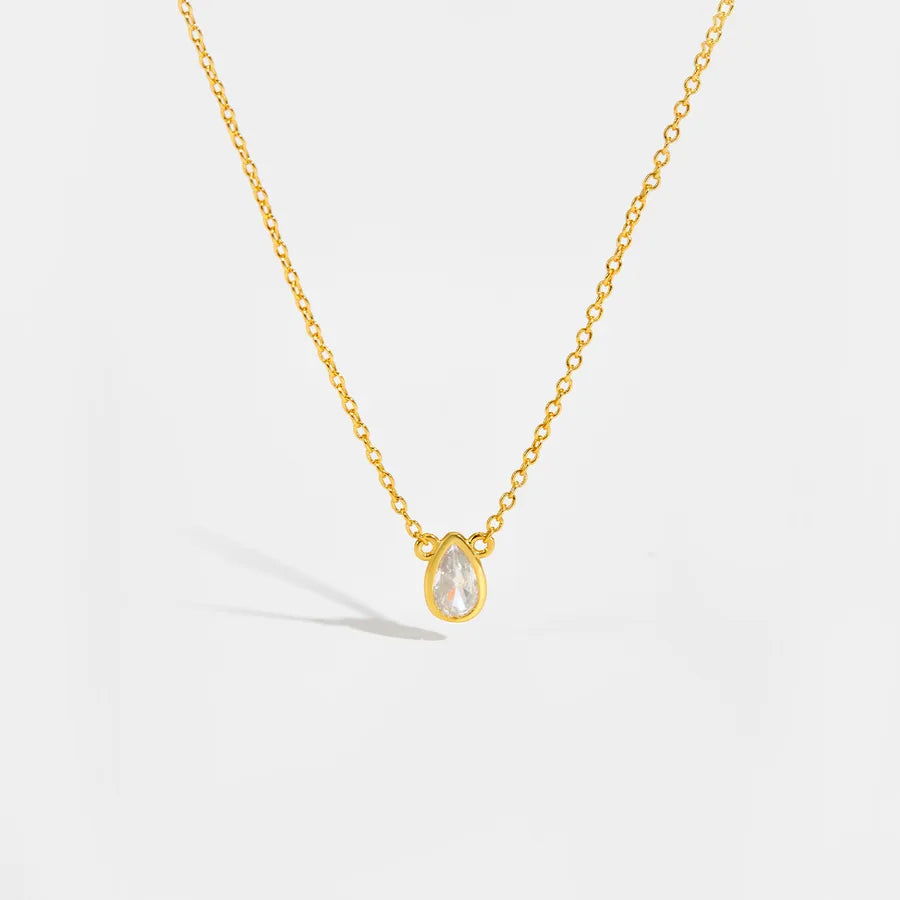Gold necklace with a teardrop-shaped pendant on a light gray background