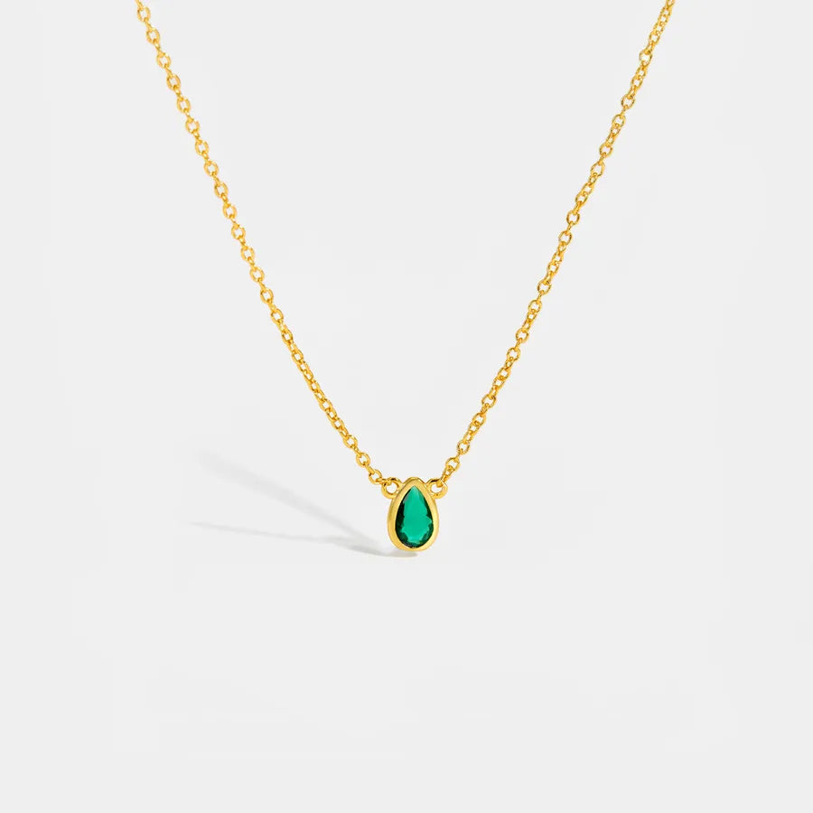 Gold necklace with a green teardrop pendant on a white background