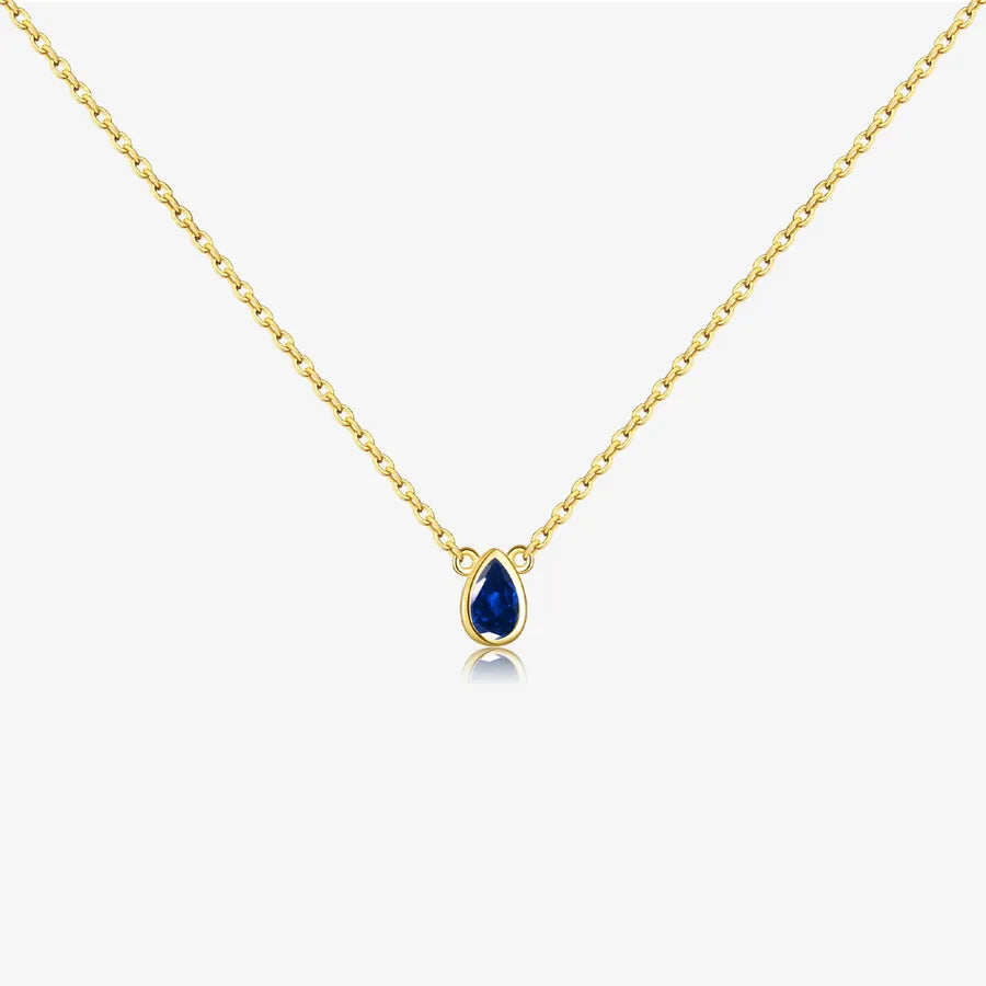 Gold necklace with a blue teardrop pendant on a white background