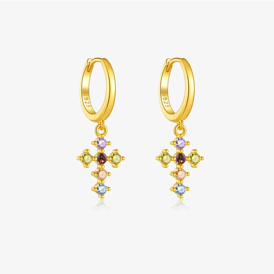 A pair of gold huggie hoop earrings with dangling cross-shaped charms set with multiple small colorful gemstones, shown on a light gray background.