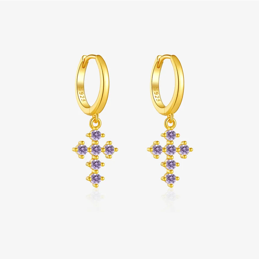A pair of gold huggie hoop earrings with dangling cross-shaped clusters of small purple gemstones, shown on a light gray background.