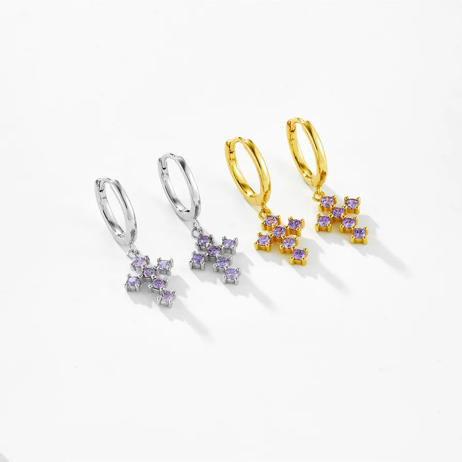 Three pairs of small hoop earrings with dangling floral clusters of clear stones in silver, yellow gold, and mixed metal finishes, arranged on a clean white background.