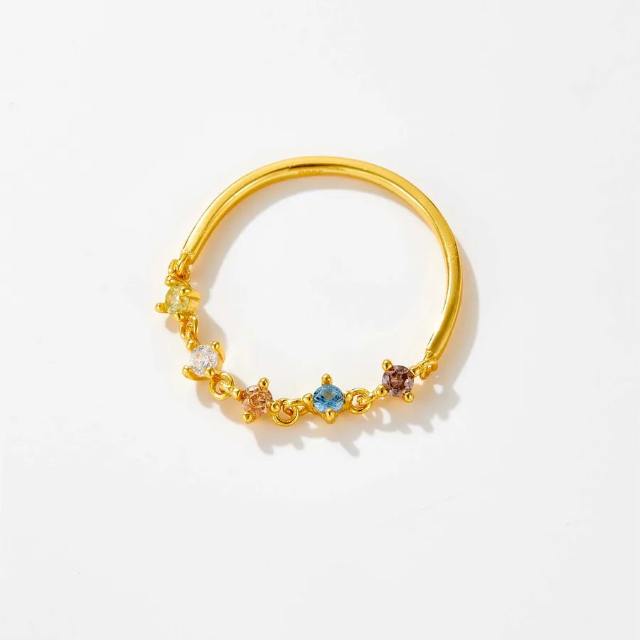 Gold ring with embedded multicolored gemstones on a white background